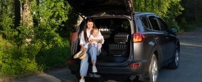 Car journey. Travel with a child by car. Mother and daughter sit in a car with an open trunk. High quality photo